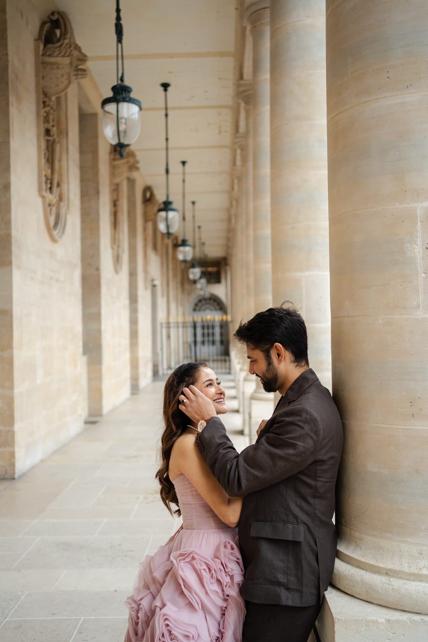 Couple embracing under historic stone arches during a romantic Paris portrait photoshoot at Palais Royal.